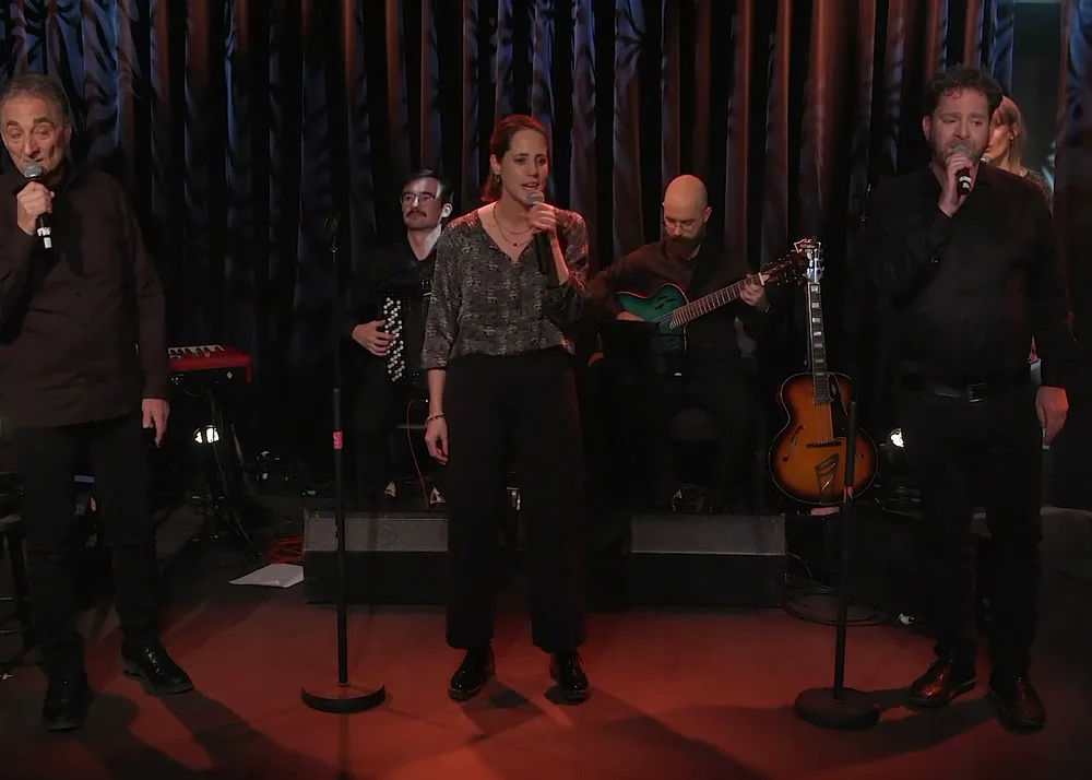 Trois chanteurs de L'Écho du Mont Brun au micro pendant une répétition, devant les musiciens